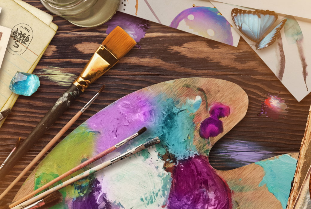 A photo of paintbrushes and a palette on a desk